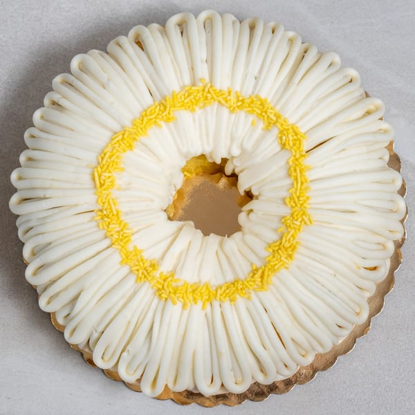 Sweet Valentine Bakery's daisy-shaped bundt cake, with white frosting petals and yellow sprinkles.