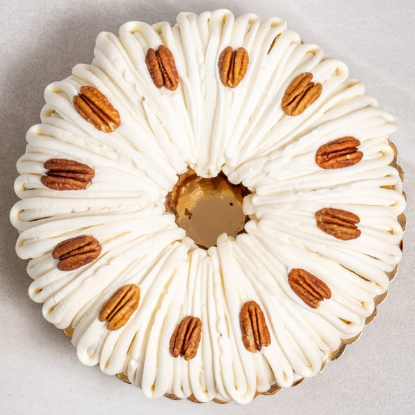 Sweet Valentine Bakery's bundt cake with white frosting and pecans on a gold scalloped tray.