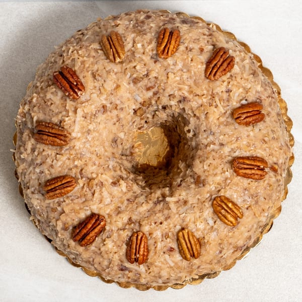 Sweet Valentine Bakery's bundt cake with coconut and pecans on a white background.