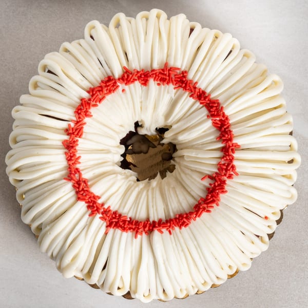 Sweet Valentine Bakery's white frosted bundt cake with red sprinkles in a circular pattern.
